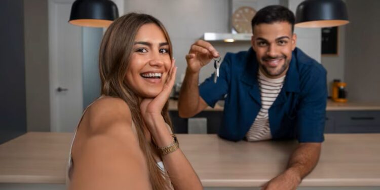 Casal feliz em casa nova, o homem exibindo chaves, representando a conquista de um imóvel com descontos.