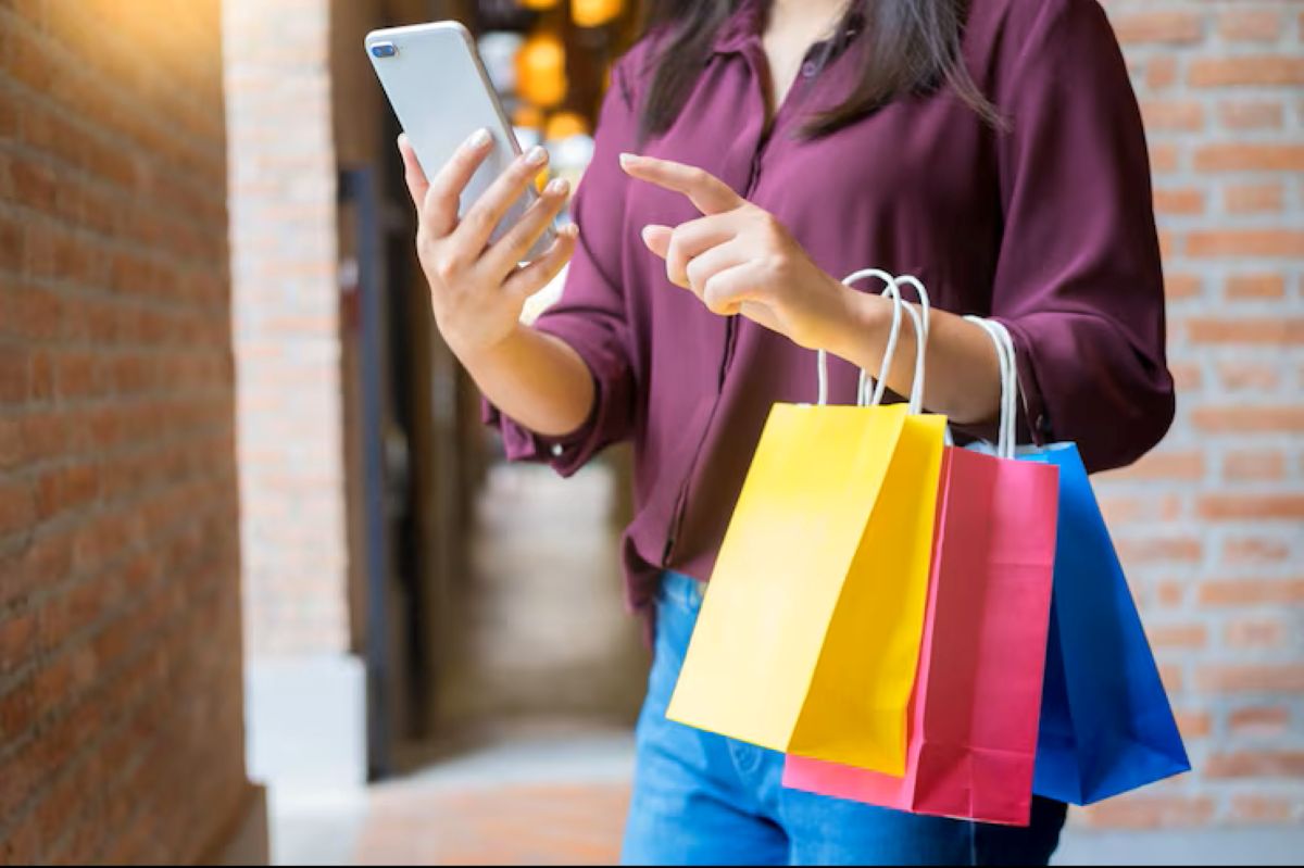 Mulher com sacolas de compras coloridas utilizando o celular para planejar suas compras durante a Black Friday.