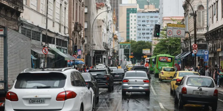 Rua movimentada com vários carros e ônibus em dia chuvoso no centro de uma grande cidade