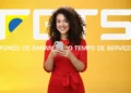 Mulher jovem sorridente com smartphone na mão, vestindo vestido vermelho, com fundo amarelo e logo do FGTS.