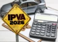 Placa amarela com IPVA 2026, carro de brinquedo, moedas e calculadora ao fundo.