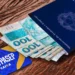 Cartão PIS/Pasep com cédulas de 100 reais e passaporte sobre fundo de madeira.