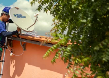 Instalador de antena satelital no telhado de uma casa, ajustando o equipamento da Brasil Antenado.