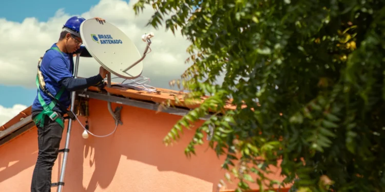 Instalador de antena satelital no telhado de uma casa, ajustando o equipamento da Brasil Antenado.