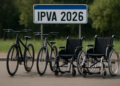 Duas bicicletas e duas cadeiras de rodas com placa IPVA 2026 ao fundo em área externa.