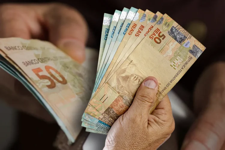 devolução valores indevidos Mão segurando notas de real, simbolizando devolução da PicPay de valores cobrados indevidamente.