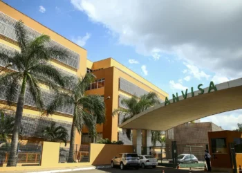 Fachada do prédio da ANVISA, com grande portaria e árvores ao redor.