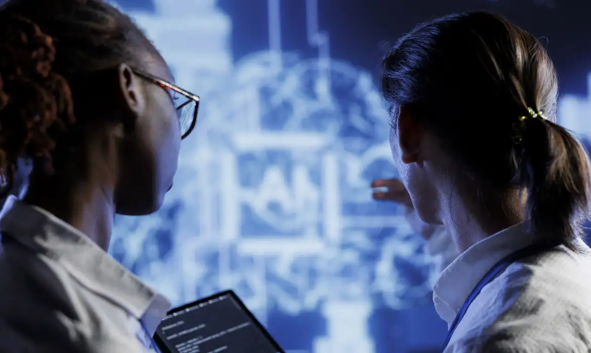 Profissionais analisando dados de inteligência artificial em laboratório Duas pessoas observam tela digital com gráficos de IA, uma segurando notebook com códigos