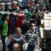Mannequins exibem roupas fitness e pessoas circulam usando máscaras em rua de comércio popular
