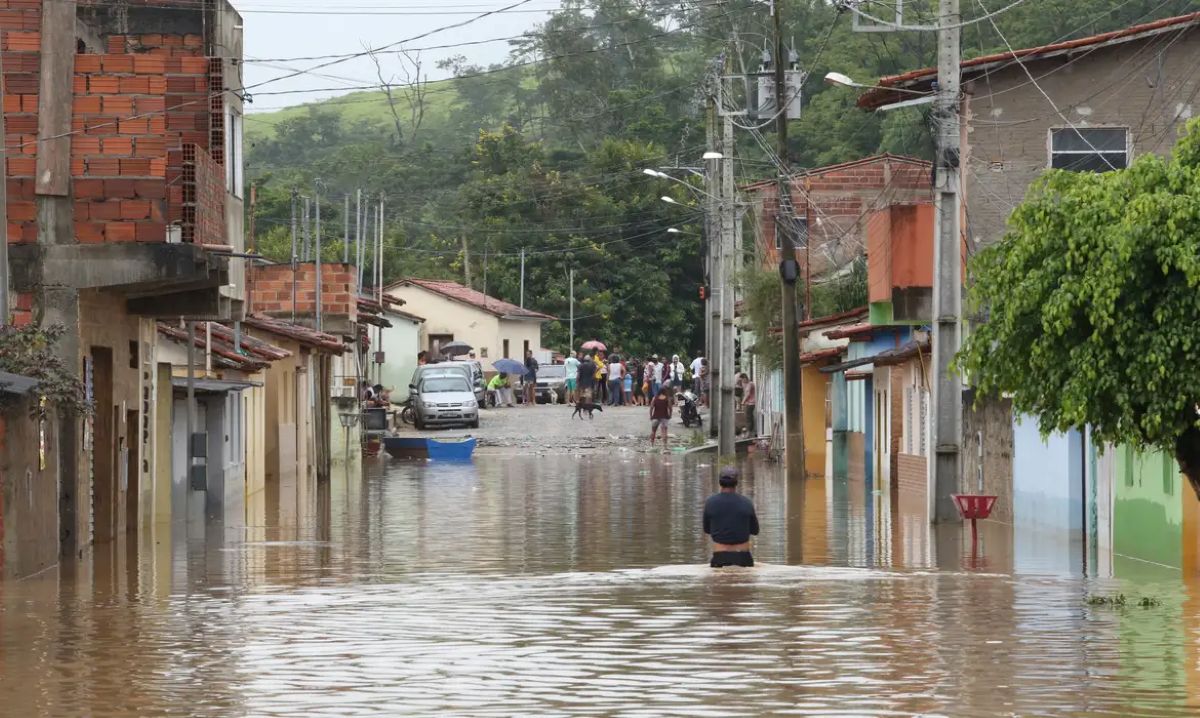 Forças Armadas e Saúde reforçam atendimento nas áreas atingidas em MG Rua alagada em Minas Gerais com moradores e equipes das Forças Armadas atuando no atendimento emergencial após fortes chuvas.