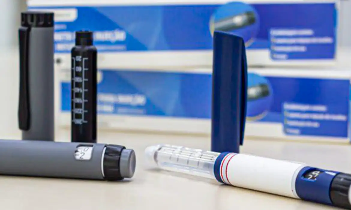 Canetas emagrecedoras sobre mesa com caixas ao fundo e o risco de pancreatite. Canetas emagrecedoras dispostas sobre superfície clara, caixas desfocadas ao fundo.