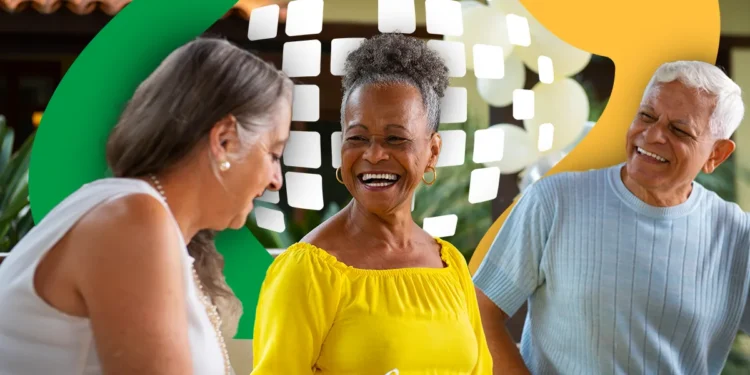 Três idosos felizes sentados juntos, um deles em destaque sorrindo e usando blusa amarela, ambiente descontraído