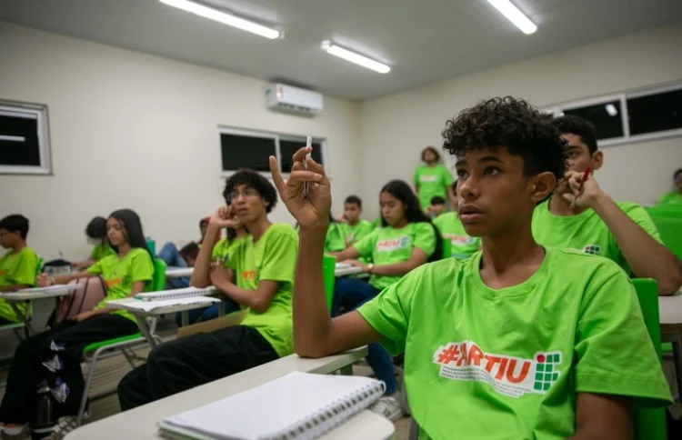 #PartiuIF 2026 Estudantes usam camisetas verdes Partiu IF 2026 enquanto acompanham aula em sala iluminada