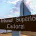 Placa marrom com a inscrição Tribunal Superior Eleitoral em destaque sob céu azul.