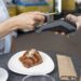 Pessoa aproxima cartão de máquina de pagamento ao comprar café e croissant em cafeteria