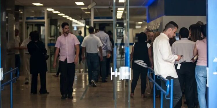Pessoas entrando e saindo de agência bancária — bancos fechados no feriado de Páscoa Sexta-feira Santa 2026