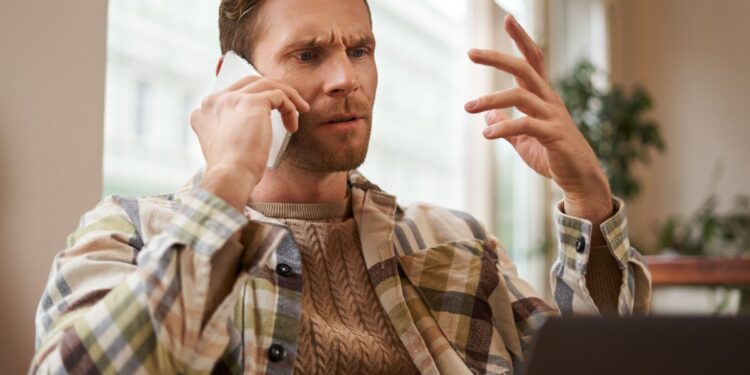 Homem preocupado falando ao telefone após receber ligação suspeita sobre conta bancária