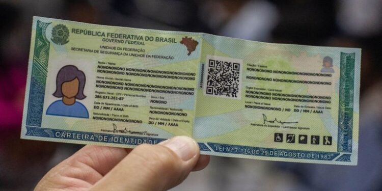 Mão segura nova Carteira de Identidade Nacional aberta com dados protegidos e QR Code visível