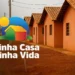 Conjunto de casas populares recém-construídas com logotipo do Minha Casa, Minha Vida na frente