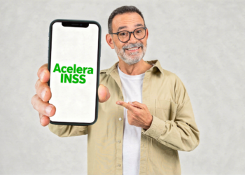 Idoso segura celular com o nome "Acelera INSS" na tela.