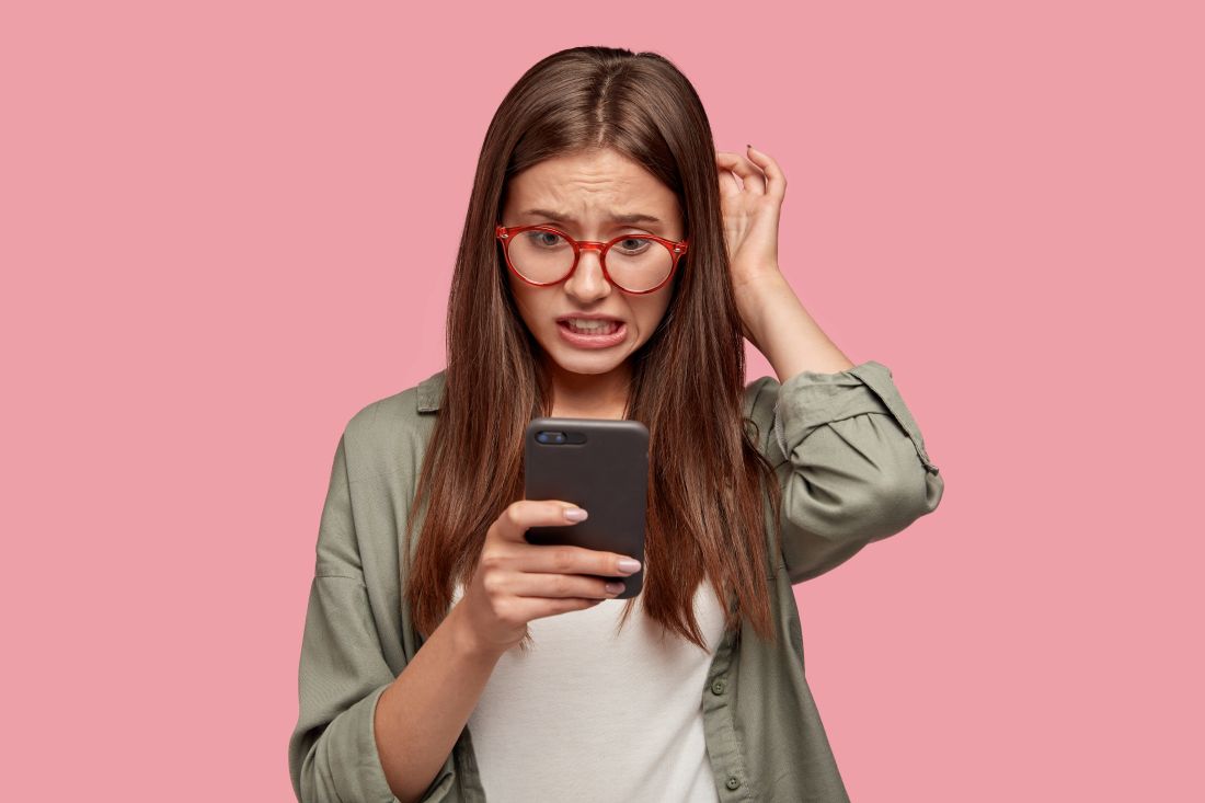 Jovem mexendo no celular preocupada.