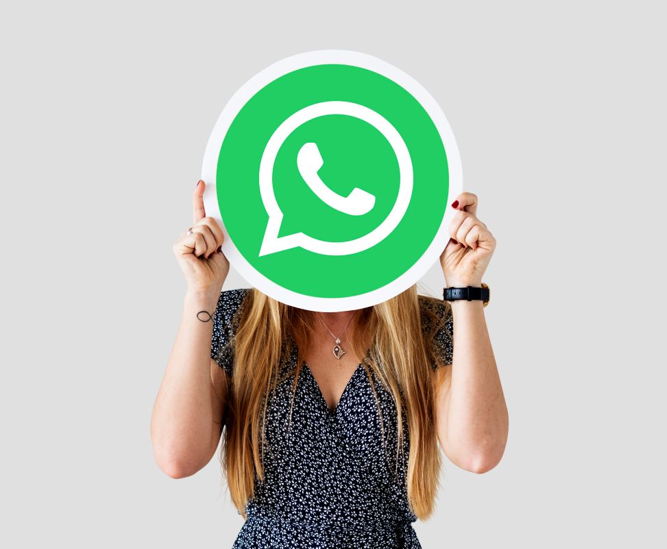 Mulher segurando placa redonda com logo do WhatsApp.