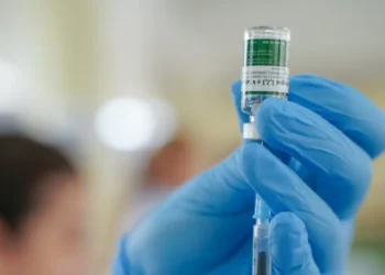 Profissional de saúde com luvas azuis prepara dose de vacina para aplicação durante a Semana de Vacinação nas Escolas