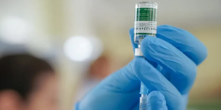 Profissional de saúde com luvas azuis prepara dose de vacina para aplicação durante a Semana de Vacinação nas Escolas