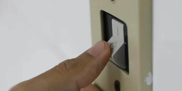 Mão aciona interruptor de luz, representando o acesso ao desconto na tarifa de energia elétrica pelo programa Luz do Povo para famílias de baixa renda em 2026.