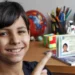 Criança sorrindo e segurando a nova Carteira de Identidade Nacional, representando a emissão gratuita da CIN em Salvador em abril de 2026.