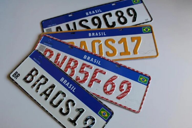Quatro placas Mercosul brasileiras empilhadas: preta particular, amarela diplomática, vermelha comercial e preta padrão.