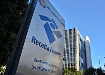 Placa da Superintendência da Receita Federal com logo do órgão em frente ao edifício do Ministério da Fazenda em Brasília.