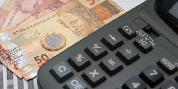 Calculadora com notas de real representando cálculo de juros de empréstimo
