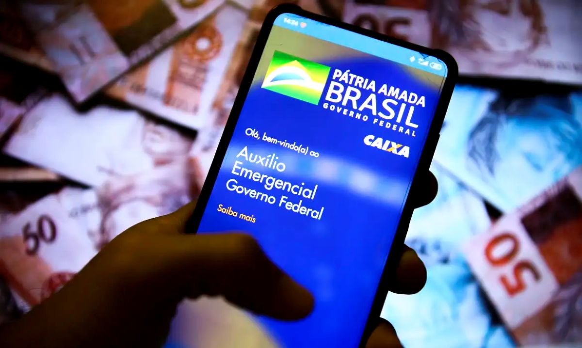 Mão segurando smartphone com aplicativo de benefício do governo federal