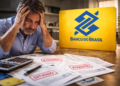 Homem preocupado com contas atrasadas ao lado do logo do Banco do Brasil