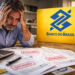 Homem preocupado com contas atrasadas ao lado do logo do Banco do Brasil