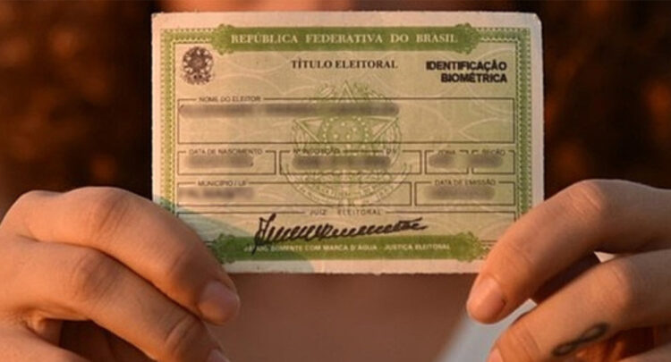 Mãos segurando título de eleitor do Brasil com identificação biométrica e brasão da República visíveis.