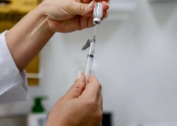 Profissional de saúde preparando dose em seringa para aplicação