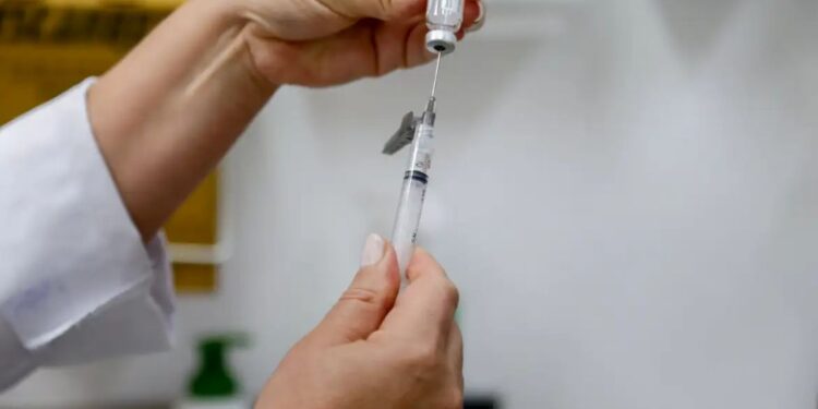 Profissional de saúde preparando dose em seringa para aplicação