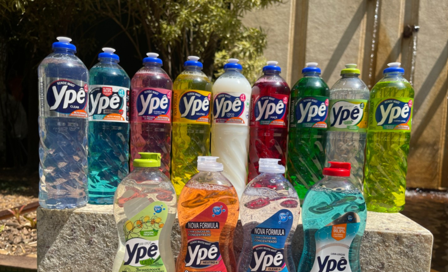 Coleção de detergentes Ypê em cores variadas sobre superfície de pedra, incluindo lava-louças e lava-roupas líquidos
