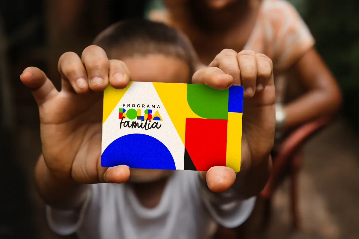Criança segura cartão do Bolsa Família com design geométrico nas cores amarelo, azul, verde e vermelho