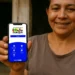 Mulher sorridente mostra celular com tela do aplicativo Bolsa Família da CAIXA, com opções de calendário e acesso