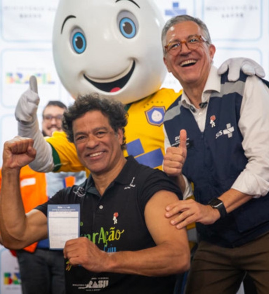 Ex-jogador Raí mostra braço vacinado ao lado do ministro Alexandre Padilha e da mascote Zé Gotinha com camisa amarela