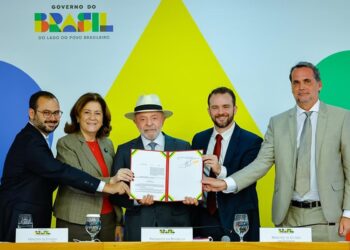 Presidente Lula, de chapéu branco, exibe documento assinado ao lado de ministros no Palácio do Planalto