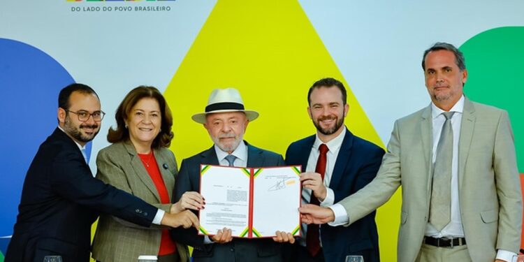 Presidente Lula, de chapéu branco, exibe documento assinado ao lado de ministros no Palácio do Planalto