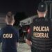 Agentes da CGU e Polícia Federal de costas durante operação noturna com viaturas ao fundo em área residencial