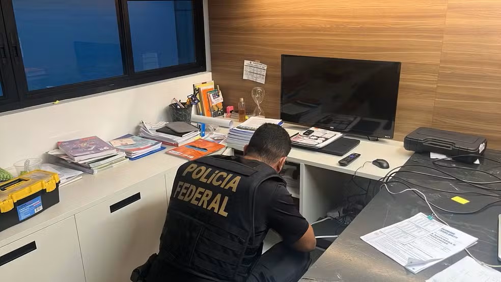 Policial federal de costas examina documentos em escritório durante cumprimento de mandado no Piauí