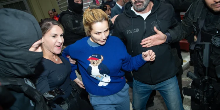 Deolane Bezerra com moletom azul da Polo sendo conduzida por policiais civis durante prisão preventiva