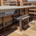 Fachada da sede da Anvisa com logo verde e amarelo, edifício bege com cobertura metálica e estacionamento