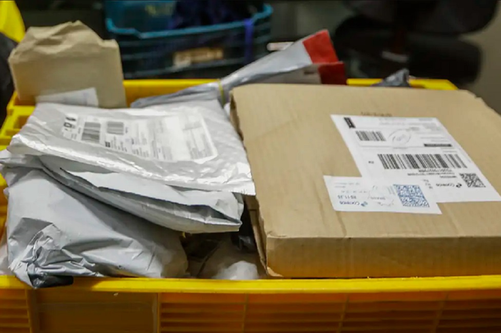 Encomendas internacionais em caixa amarela, com pacotes prateados e caixa de papelão com etiquetas e QR codes